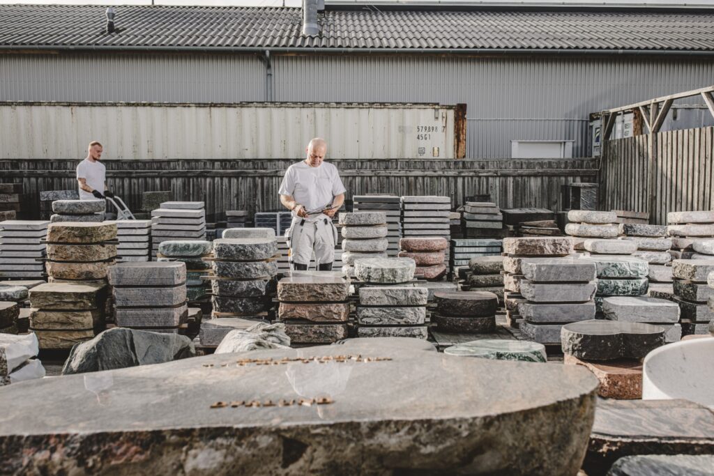 Mand inspicerer udstillede mindesten, med en medarbejder i baggrunden.