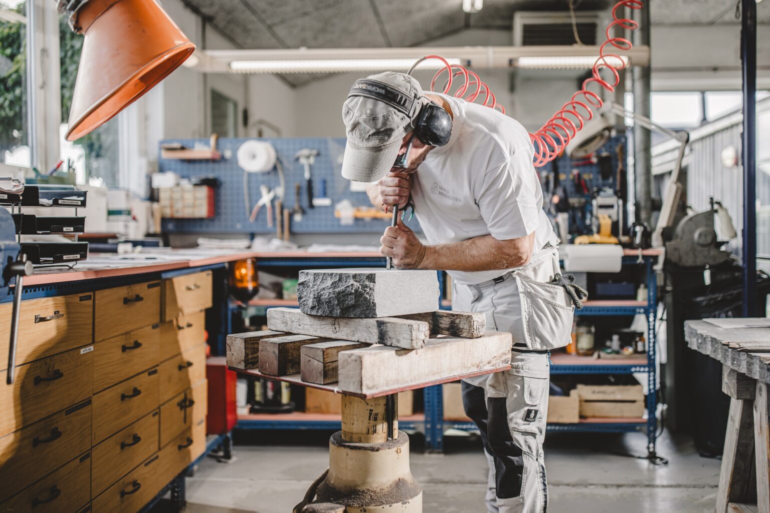 Stenhugger arbejder på en mindesten i værkstedet med værktøj.