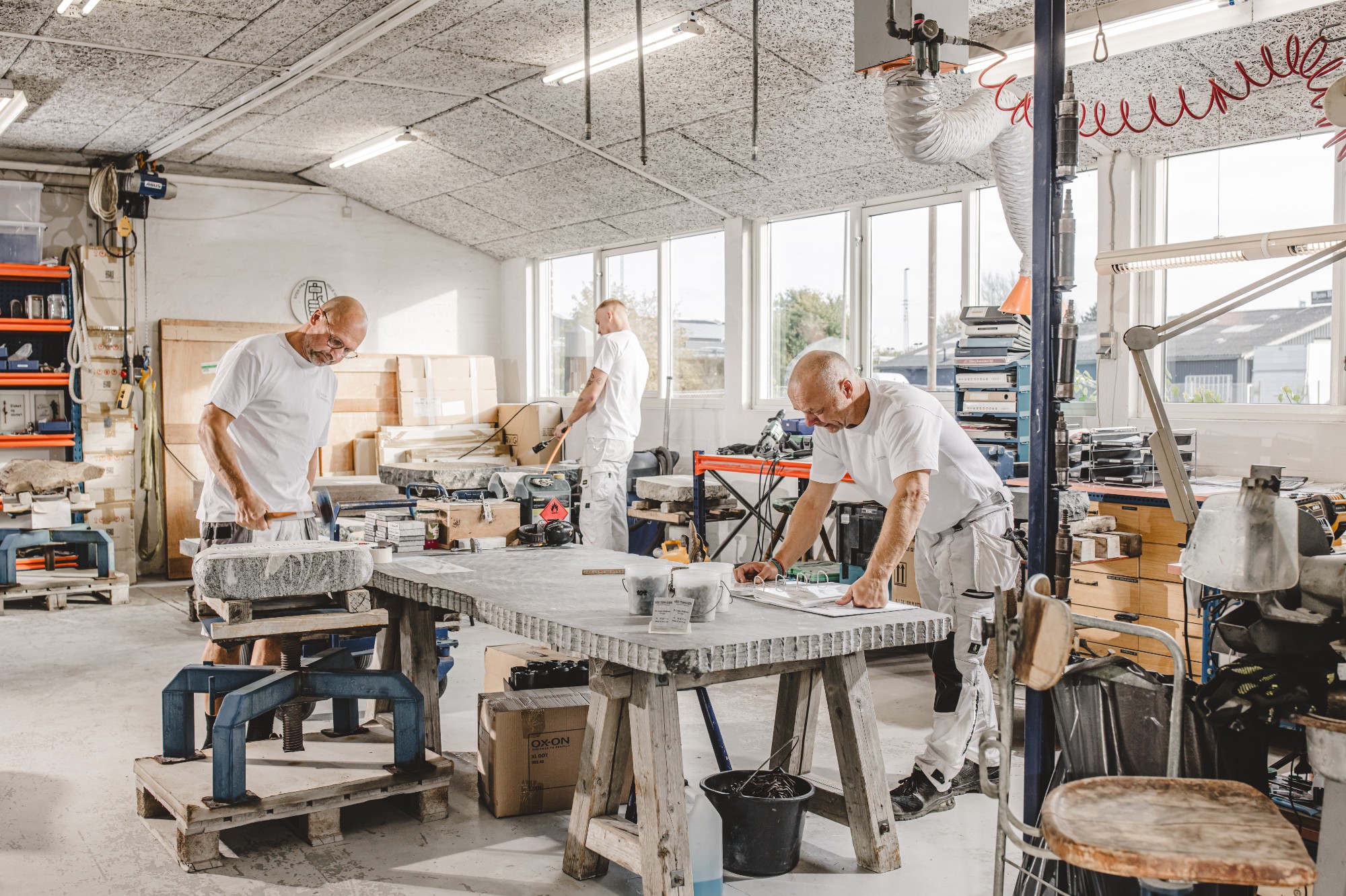 Mænd i værksted, der udformer unikke mindesten med fokus på detaljer og kvalitet.