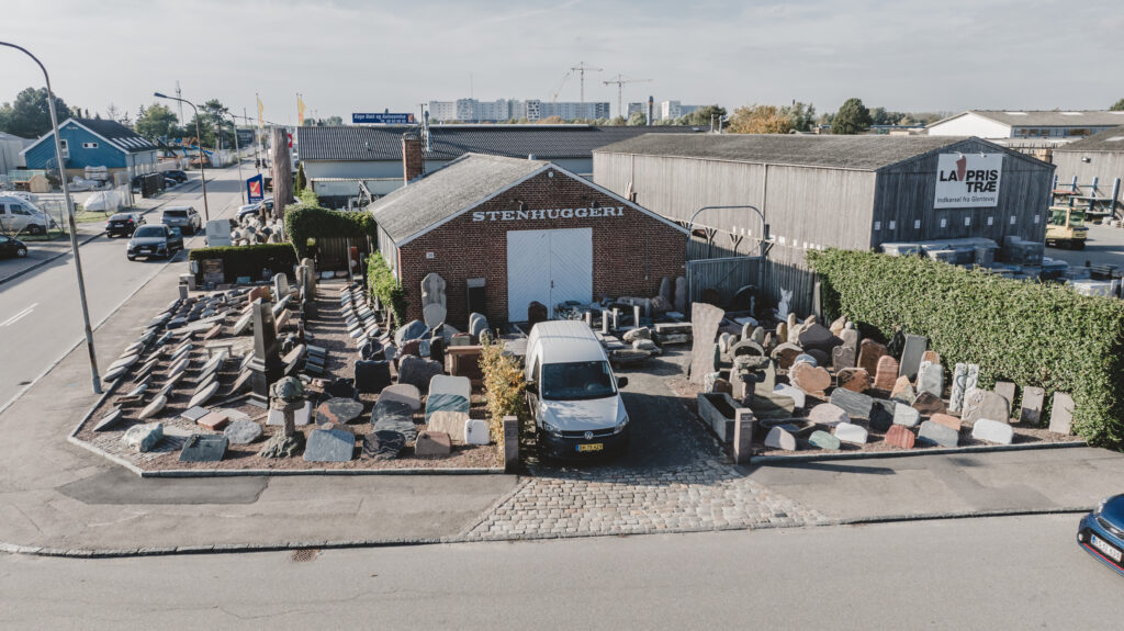 Luftfoto af Unika Mindesten Køge udstilling med gravsten, bygning og varevogn.
