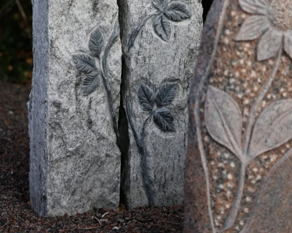 Kompakt urnesten i mørk granit med indgraveret navn og personligt motiv til urnegravsted.