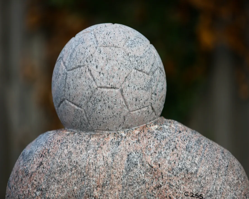 Skulpturel mindesten i granit med personlig håndlavet udskæring af fodbold.