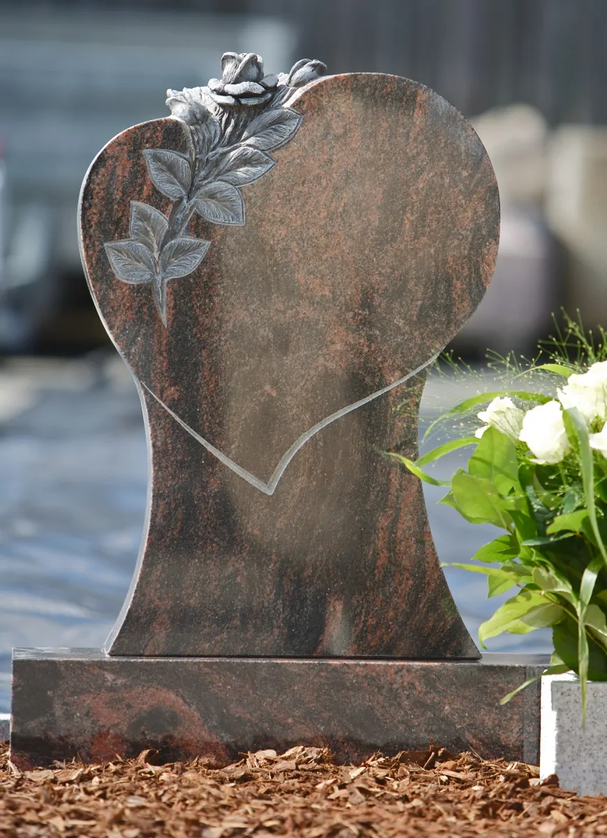 Håndlavet urnesten formet som hjerte i rødbrun granit med udskåret rose.