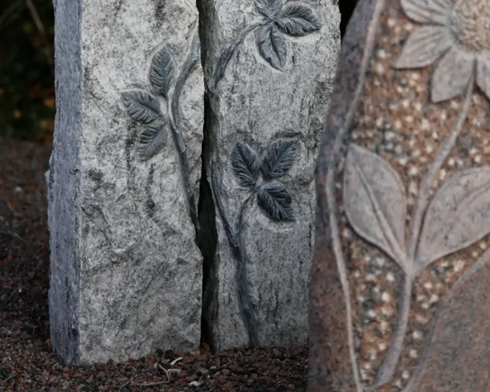 Kompakt urnesten i mørk granit med indgraveret navn og personligt motiv til urnegravsted.